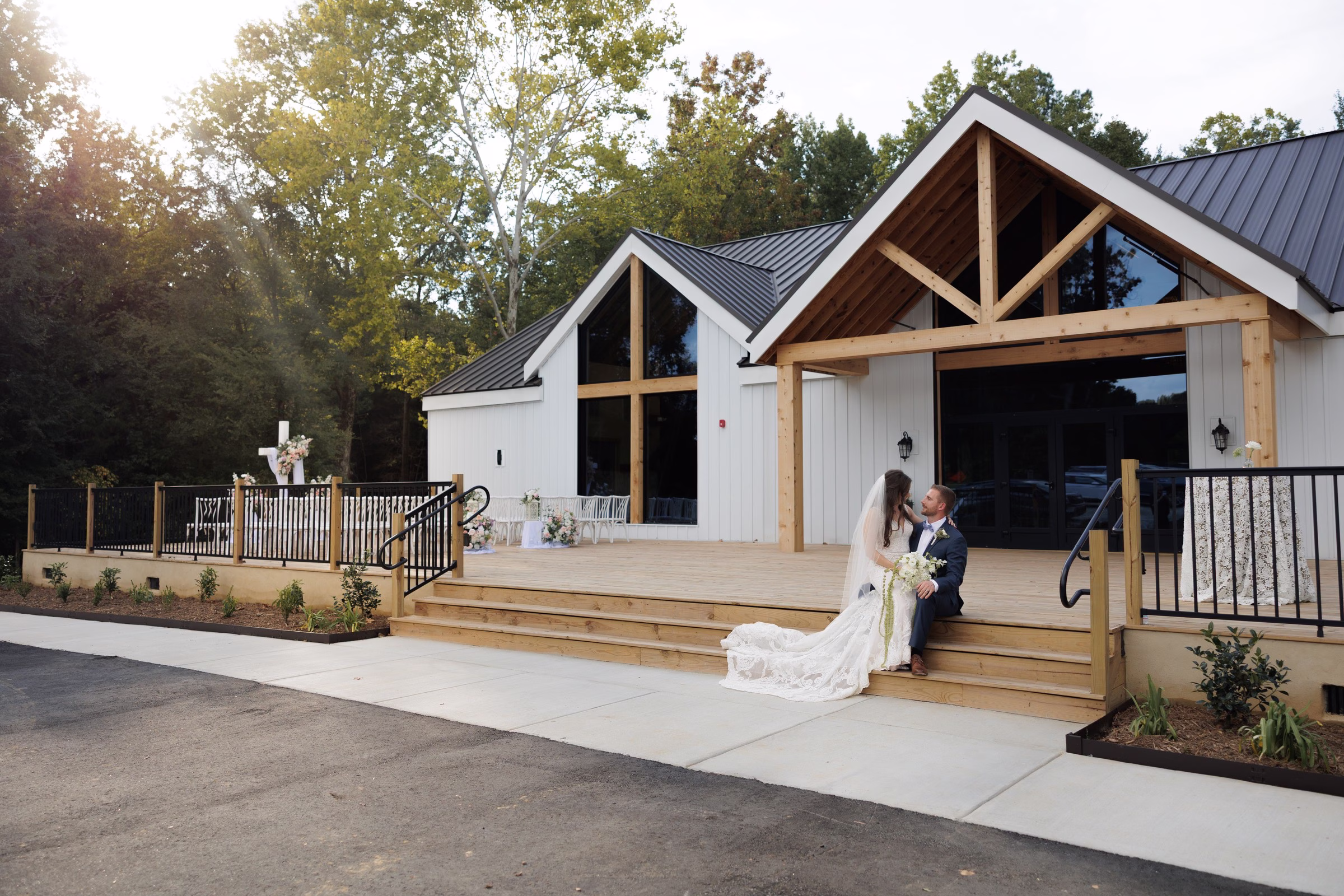 Bride and groom sitting on the wooden deck steps of The Grand wedding venue chapel in York SC near Charlotte NC sharing a quiet moment after their ceremony