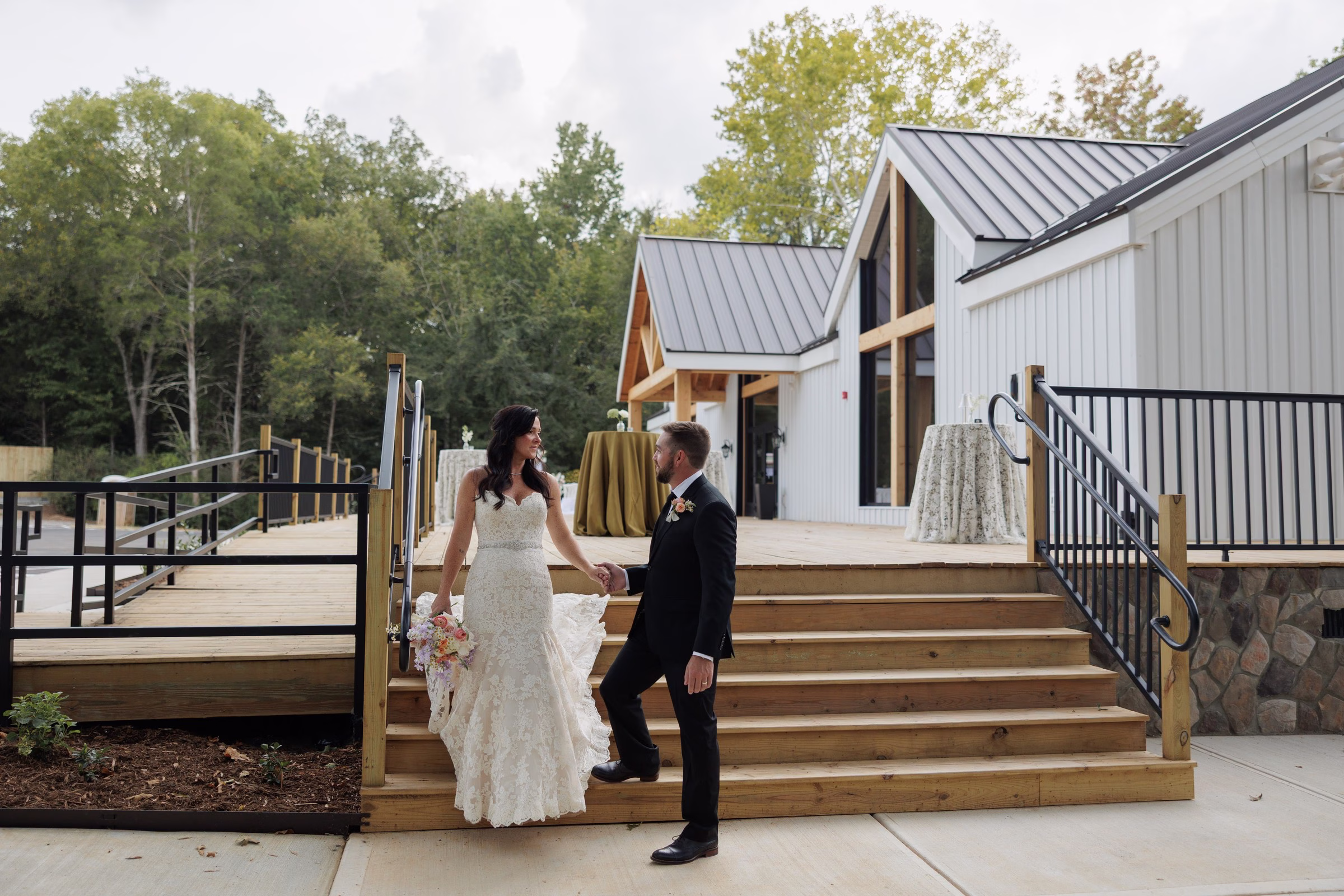 Bride and groom holding hands on wooden staircase steps at The Grand wedding venue in York SC near Charlotte NC