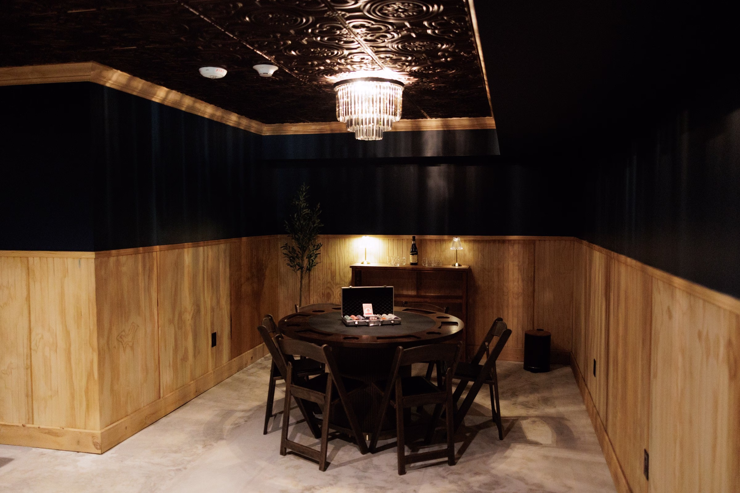 Elegant grooms lounge with poker table, crystal chandelier, and wood paneling at The Grand wedding venue in York SC near Charlotte NC