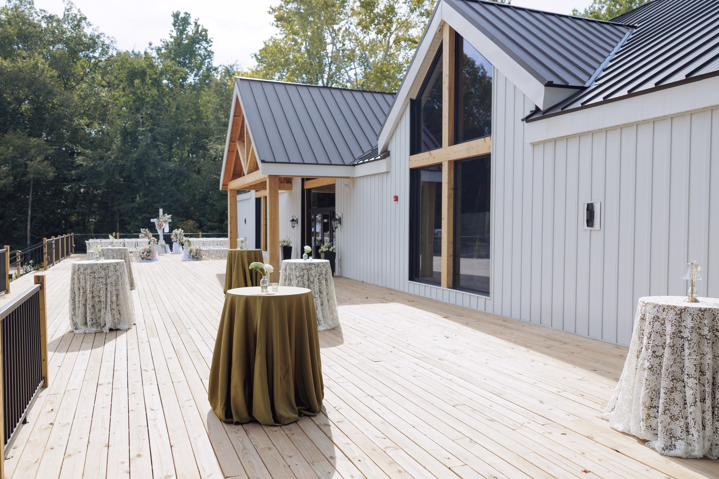 Elegant outdoor deck cocktail hour setup with olive green and lace tablecloths at The Grand wedding venue in York SC near Charlotte NC