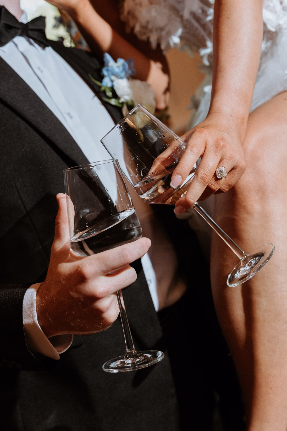 Bride and groom clinking champagne flutes during wedding toast at The Grand wedding venue in York SC near Charlotte NC, bride wearing a stunning halo diamond engagement ring